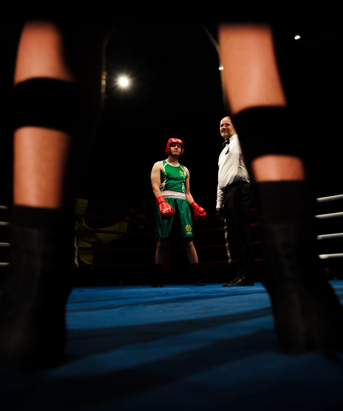 Boxer and referee framed through the ring ropes.