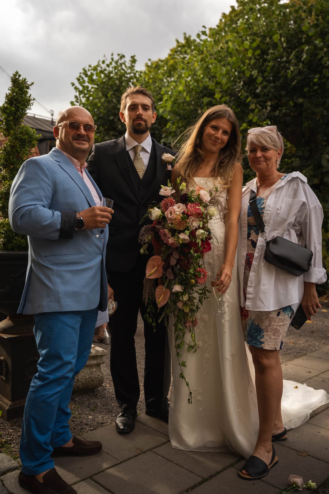 Newly married couple with guests at an outdoor wedding.