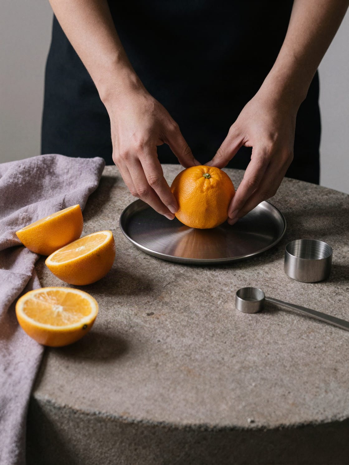 Editorial food-styling concept with hands arranging citrus on brushed steel.